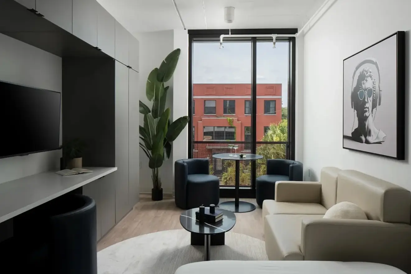 Bright corner with modern gray loveseat, large windows, and city view.